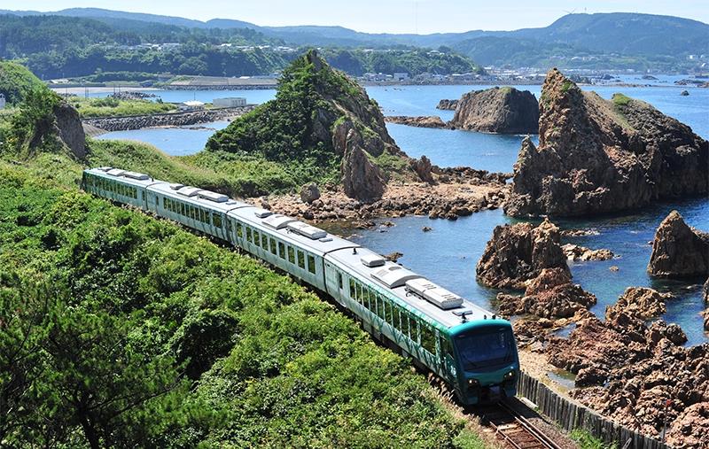 Scenic train traveling along rocky coastline in rural Japan